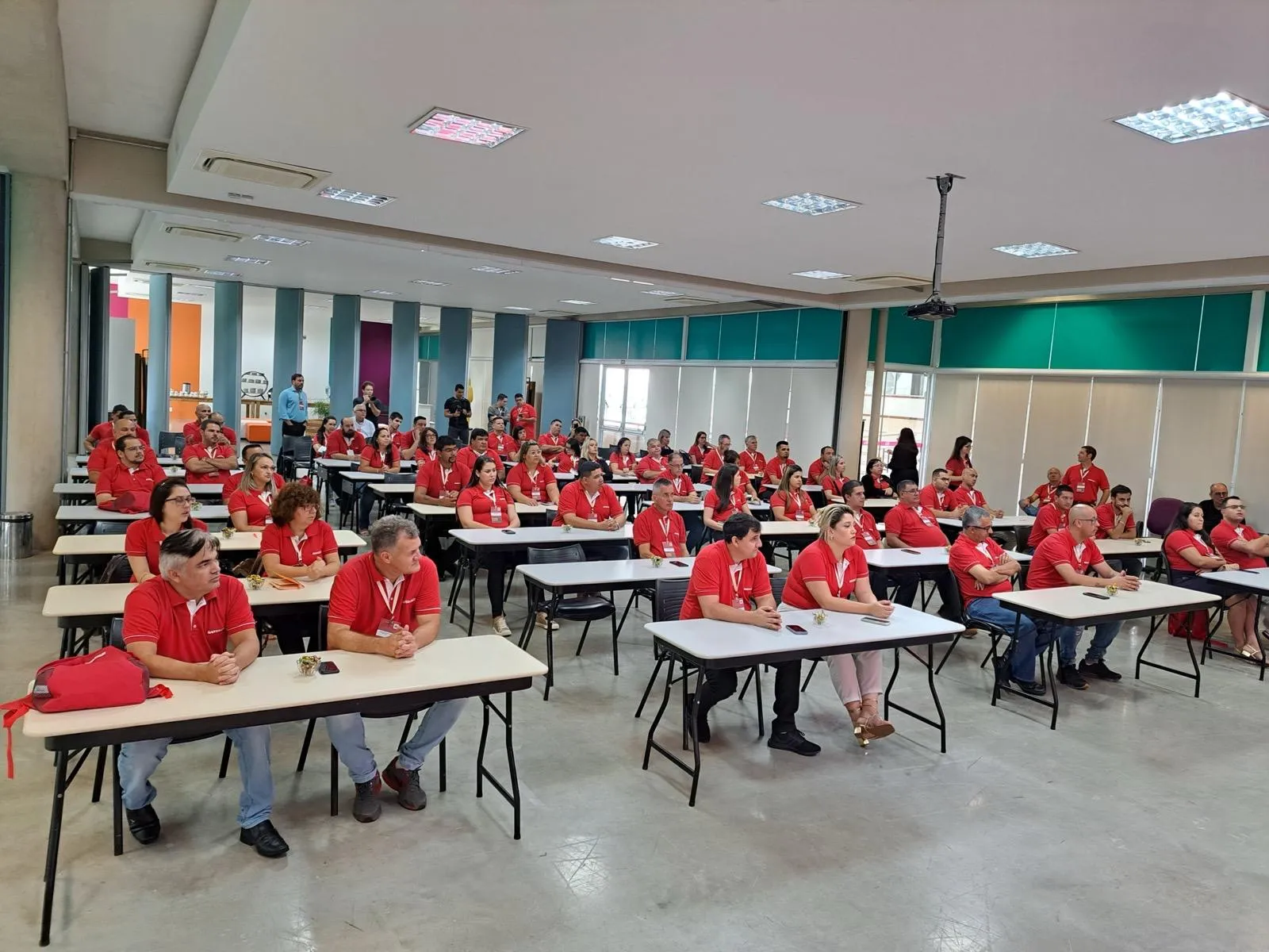 Participantes reunidos em sala com mesas